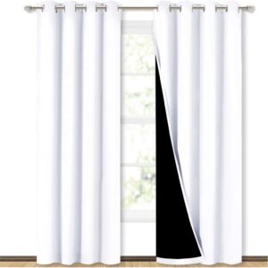 NICETOWN blackout curtains in white hanging from grommet top rod in a bedroom window